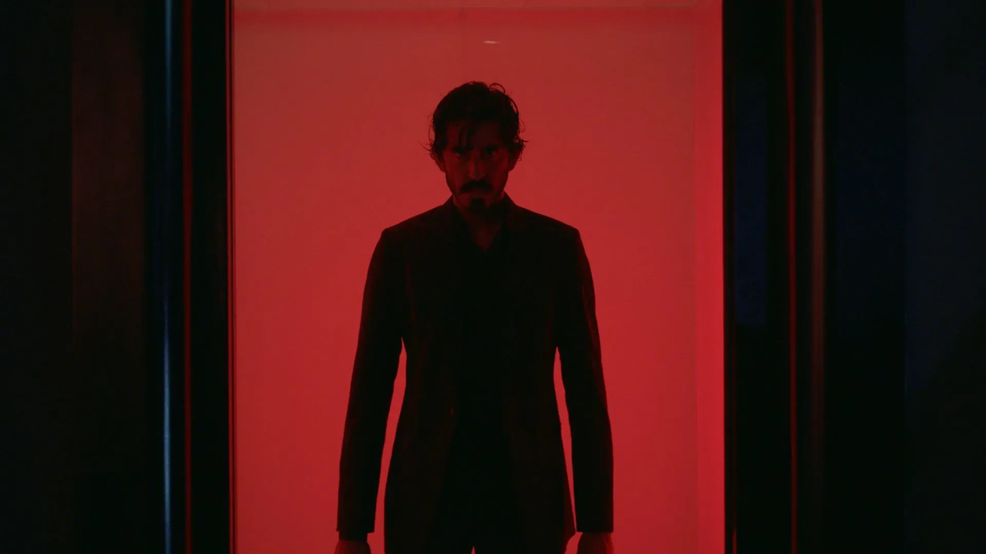 Dev Patel against a harsh red background in the film Monkey Man