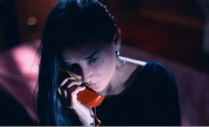 Demi Moore talking into a red phone in the film The Substance