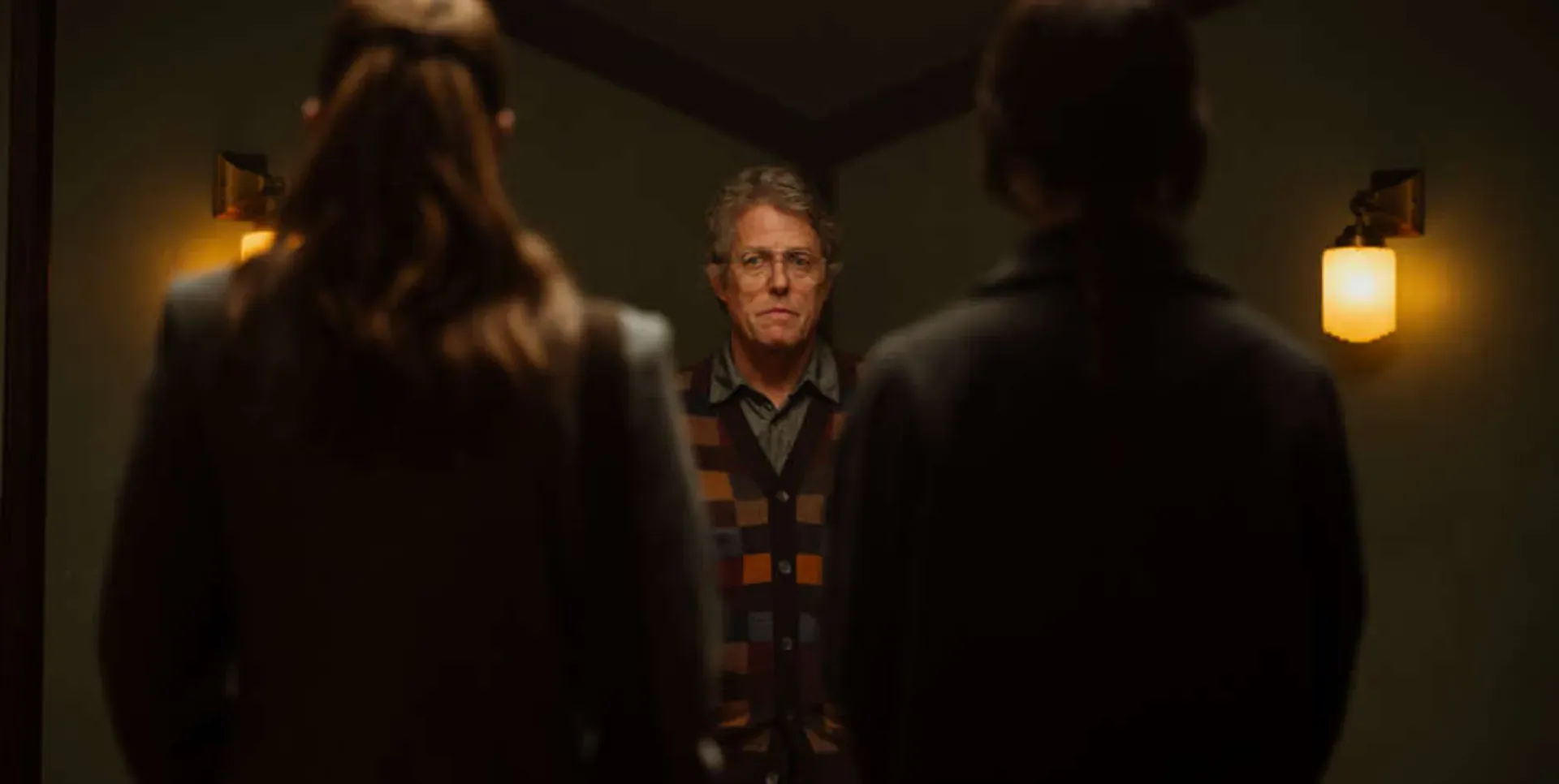 Hugh Grant standing next to two women in the film Heretic